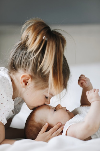 Foto grátis a irmã mais velha está beijando a menina na testa com os olhos fechados