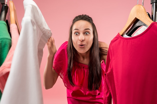 A jovem bonita olhando vestidos e experimentando enquanto escolhe na loja