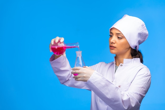 A jovem enfermeira faz a reação química com muita atenção.