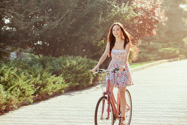 A jovem garota com bicicleta no parque