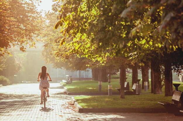 A jovem garota com bicicleta no parque