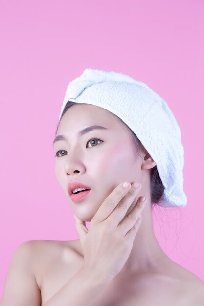 A jovem mulher Ásia com pele fresca limpa toca em possuir a cara, expressões faciais expressivos, cosmetologia e termas.