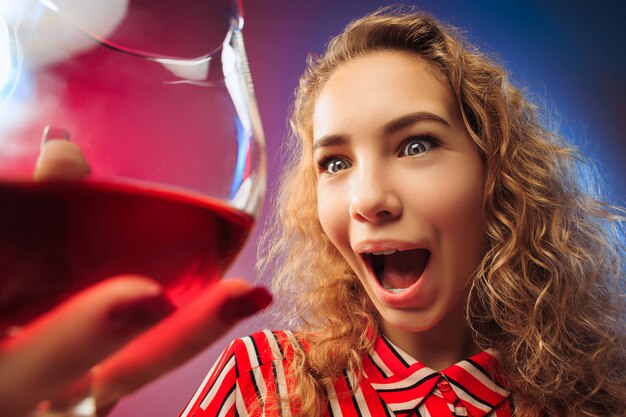 A jovem surpresa em roupas de festa, posando com um copo de vinho.