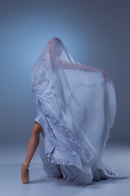 Foto grátis a linda bailarina dançando em um vestido longo azul sobre fundo azul