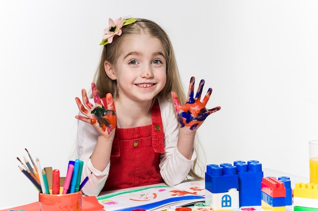 A linda garotinha com as mãos na pintura