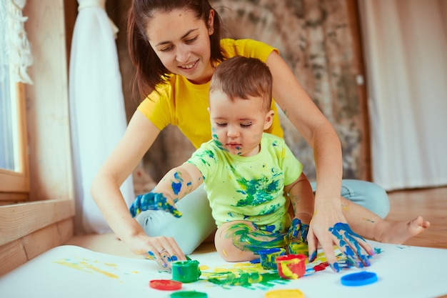 A mãe com filho pintando um grande papel com as mãos