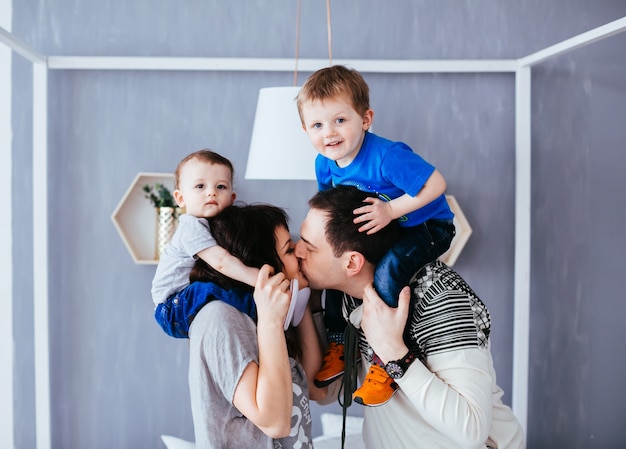 A mãe e o pai beijando e segurando os ombros de seus filhos