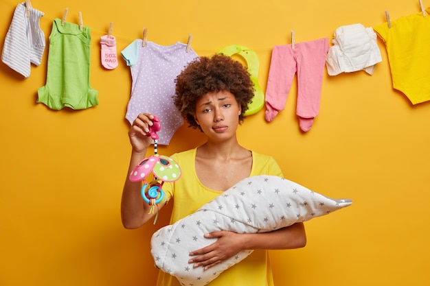 Foto grátis a mãe étnica exausta passa um tempo precioso com o bebê recém-nascido, segura os movimentos, tem aparência cansada, fadiga das noites sem dormir e amamentação do bebê. cena de proteção e amor. conceito de maternidade