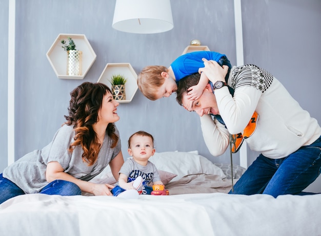 Foto grátis a mãe, pai e filhos sentados na cama