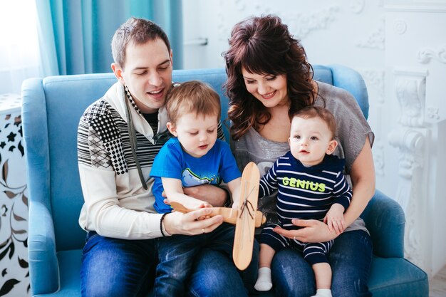 A mãe, pai e filhos sentados no sofá