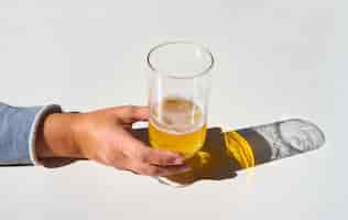 Foto grátis a mão da fêmea pega um copo de cerveja com a sombra refletida na mesa branca