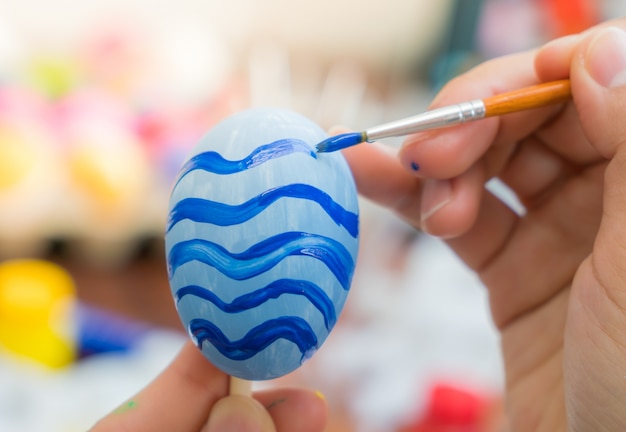 A mão da mulher que decora ovos de páscoa