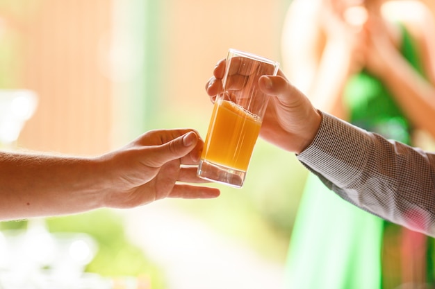 A mão do homem alcança um copo com suco fresco para outro homem