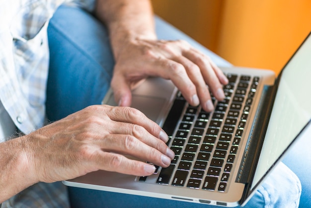 A mão do homem no teclado do laptop