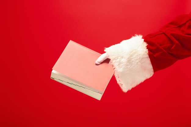 A mão do Papai Noel segurando um caderno vermelho