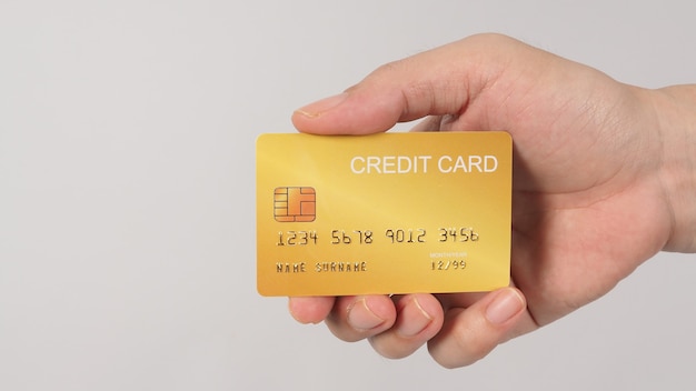 A mão está segurando o cartão de crédito ouro isolado no fundo branco.