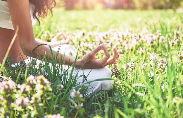 A meditação de ioga em um parque na grama é uma mulher saudável em repouso.