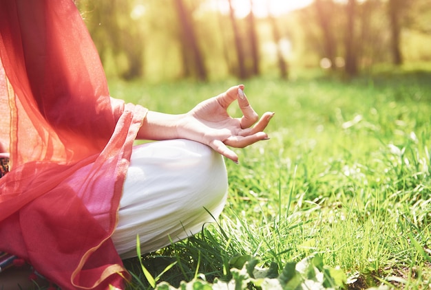 A meditação de ioga em um parque na grama é uma mulher saudável em repouso.