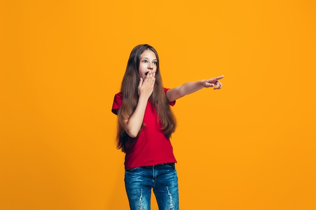 A menina adolescente feliz apontando para algo