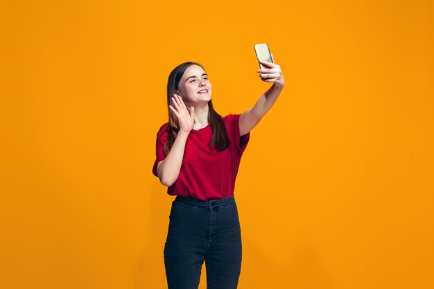 A menina adolescente feliz em pé e sorrindo