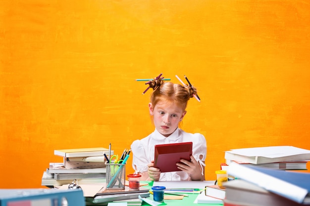 A menina adolescente ruiva com muitos livros em casa. fotografia de estúdio