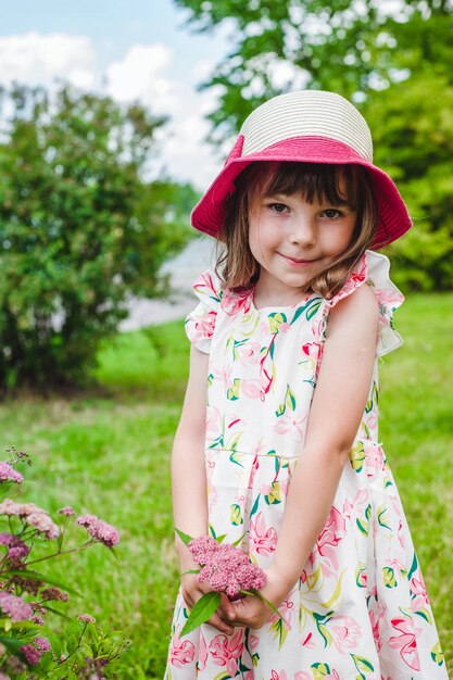 A menina adorável com um buquê de flores silvestres