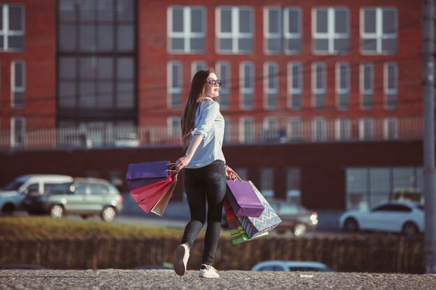 Foto grátis a menina andando com as compras nas ruas da cidade