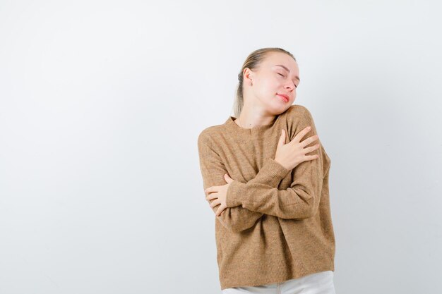 A menina bonita está se abraçando no fundo branco