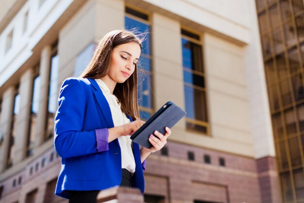 A menina checa seu tablet de pé na rua