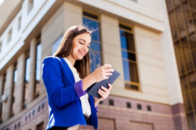 A menina checa seu tablet de pé na rua