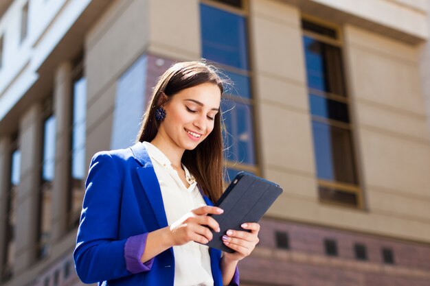 A menina checa seu tablet de pé na rua