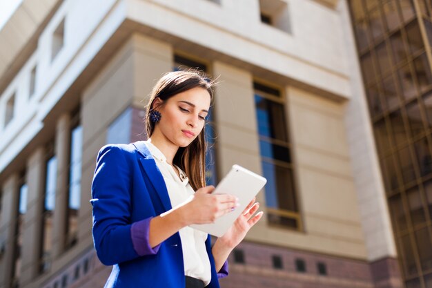 A menina checa seu tablet de pé na rua