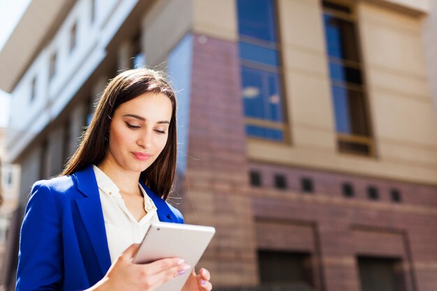 A menina checa seu tablet de pé na rua