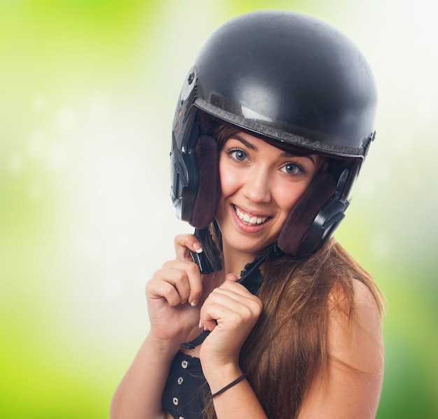 A menina de sorriso que prende o capacete preto na cabeça.