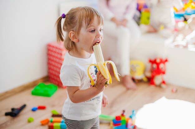 A menina é absorvida com comer banana