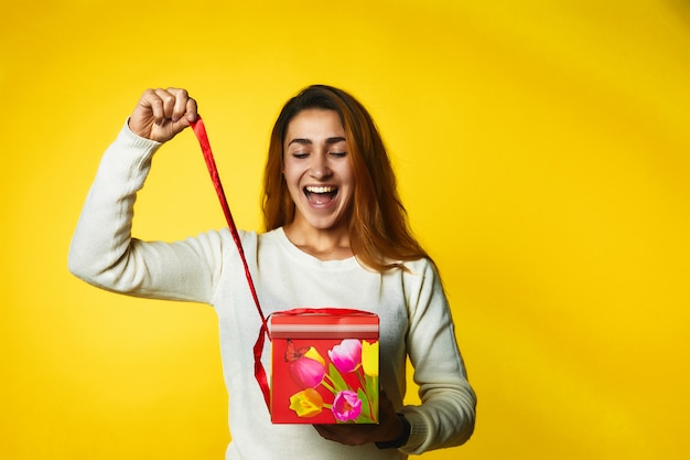 A menina está desembalando um presente e está muito feliz