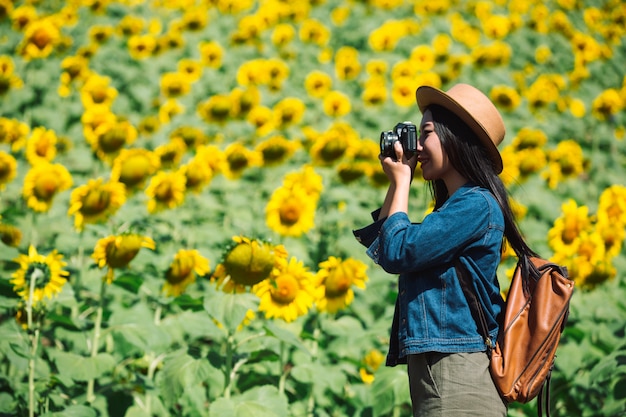 A menina está feliz em tirar fotos no campo de girassol.