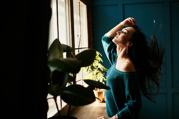 A menina está feliz por estar no sol da manhã em seu apartamento