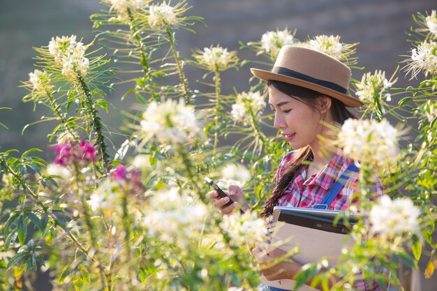 A menina está tirando fotos de flores com uma câmera móvel.