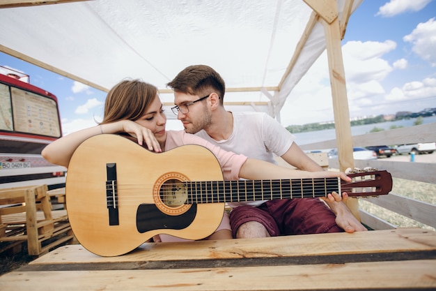 A menina inclina-se em uma guitarra olhando para o namorado