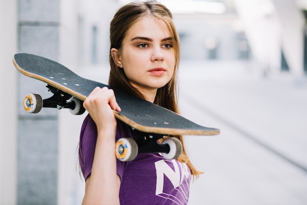 Foto grátis a menina mantém o skate sobre o ombro direito