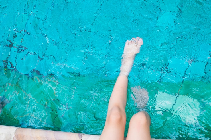 Foto grátis a menina relaxa os pés com água na piscina.