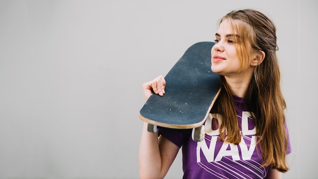 Foto grátis a menina segura o skate sobre o ombro