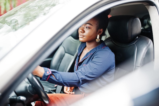 Foto grátis a mulher africana do negócio rico senta-se no banco do motorista no carro de prata suv com porta aberta