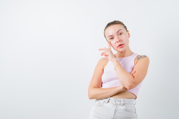 A mulher bonita está mostrando seu olho no fundo branco