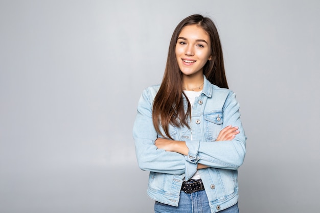 A mulher bonita que veste o revestimento ocasional da sarja de Nimes sobre a parede isolada entrega junto e os dedos cruzados sorrindo relaxado e alegre. Sucesso e otimista