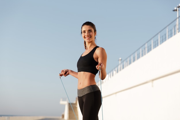 A mulher de esportes feliz jovem sorridente faz exercícios de esporte