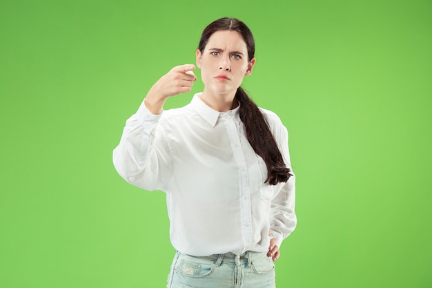 A mulher de negócios arrogante apontar e querer você, retrato de closeup de metade do comprimento sobre fundo verde.