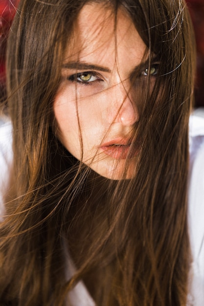 Foto grátis a mulher deslumbrante de olhos verdes senta-se diante de flores vermelhas