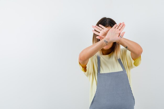 A mulher está cobrindo o rosto com as mãos cruzadas no fundo branco